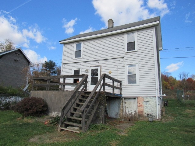 rear view of property featuring a yard and a wooden deck