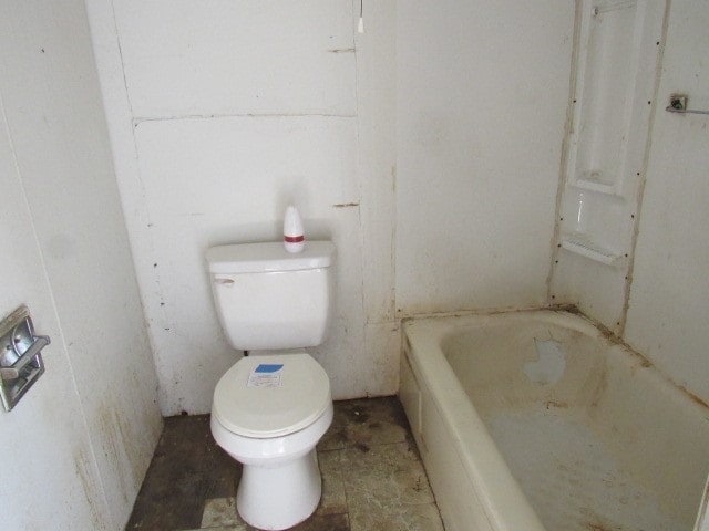 bathroom featuring a tub to relax in and toilet