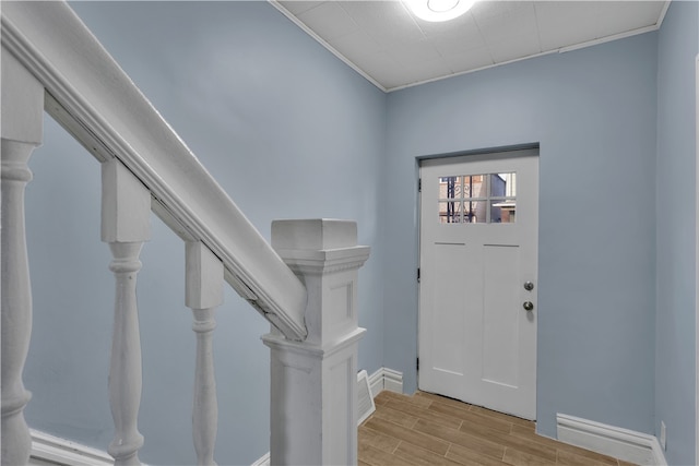 foyer entrance featuring crown molding and light hardwood / wood-style flooring