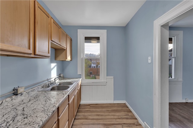 kitchen featuring light hardwood / wood-style flooring, sink, and light stone counters