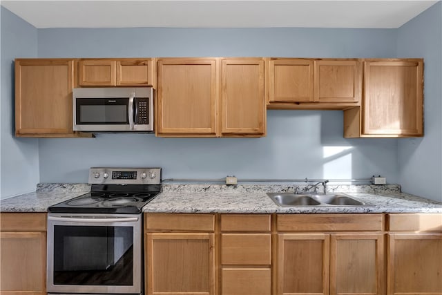 kitchen featuring light stone counters, stainless steel appliances, light brown cabinetry, and sink