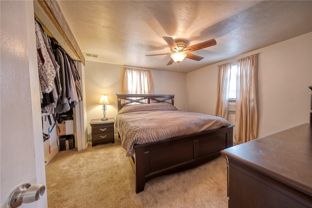 bedroom featuring light carpet, a textured ceiling, and ceiling fan