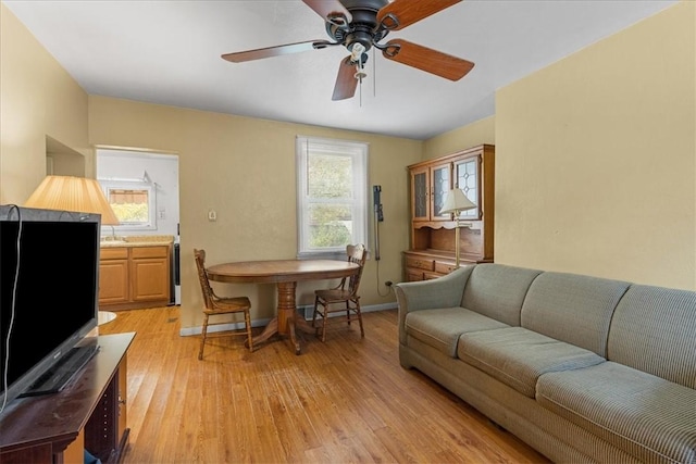 living room with ceiling fan, light wood-type flooring, and sink