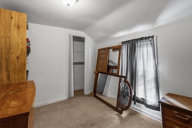 unfurnished bedroom featuring baseboards, vaulted ceiling, carpet, and a closet
