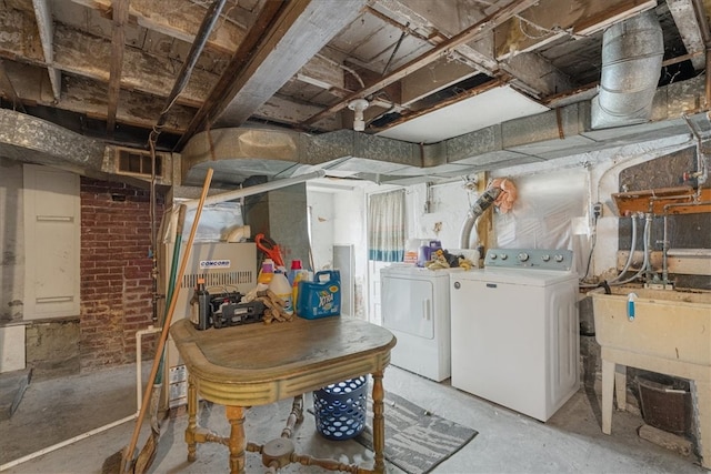 basement featuring washing machine and dryer and brick wall