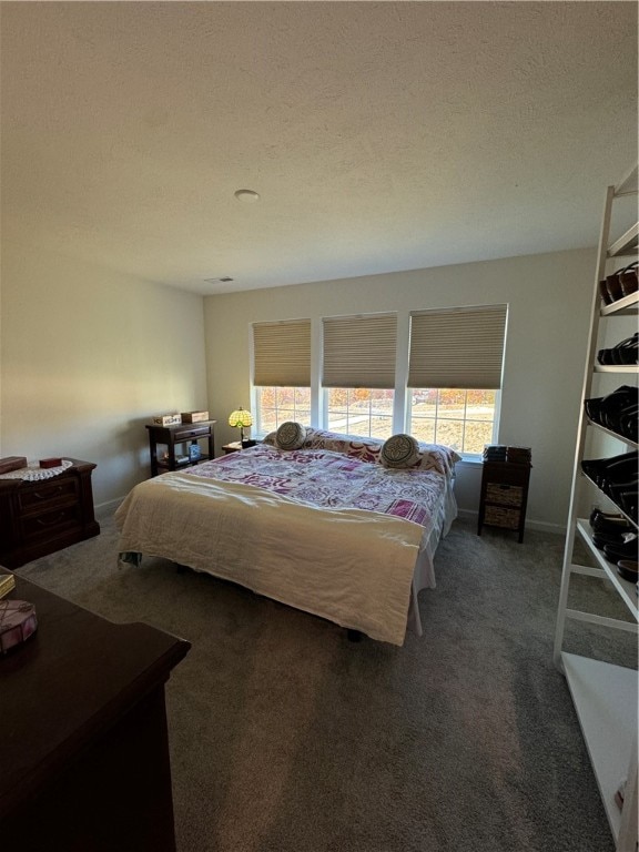 bedroom with a textured ceiling and dark colored carpet