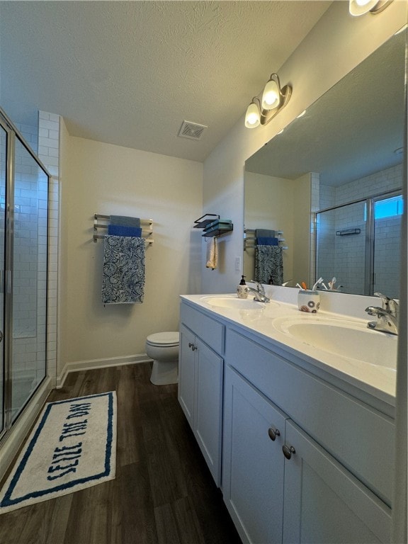 bathroom with toilet, hardwood / wood-style floors, vanity, and a shower with door