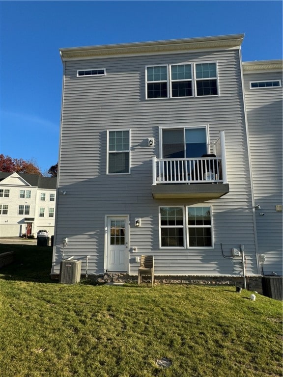 back of property featuring a balcony, central AC, and a yard