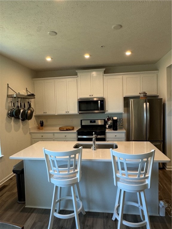 kitchen featuring white cabinets, a kitchen island with sink, stainless steel appliances, and dark hardwood / wood-style floors