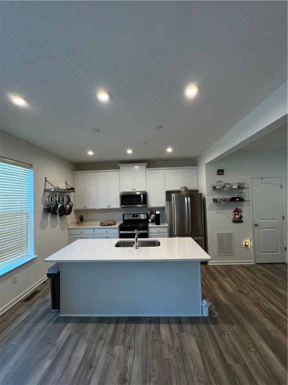 kitchen with white cabinetry, stainless steel appliances, a center island with sink, and dark hardwood / wood-style flooring