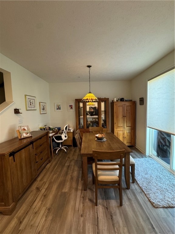 dining space with dark hardwood / wood-style floors and a textured ceiling