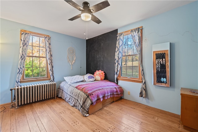 bedroom with radiator heating unit, wood-type flooring, and ceiling fan