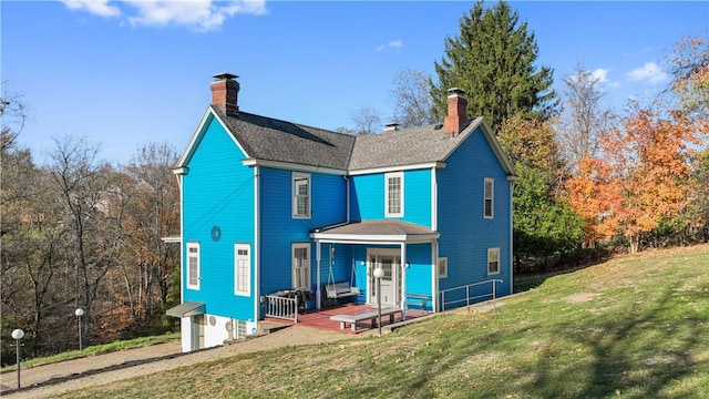 rear view of house with covered porch and a lawn