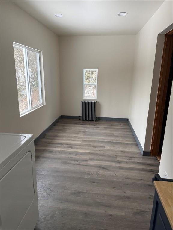 laundry room with dark hardwood / wood-style flooring, radiator, and washer / clothes dryer