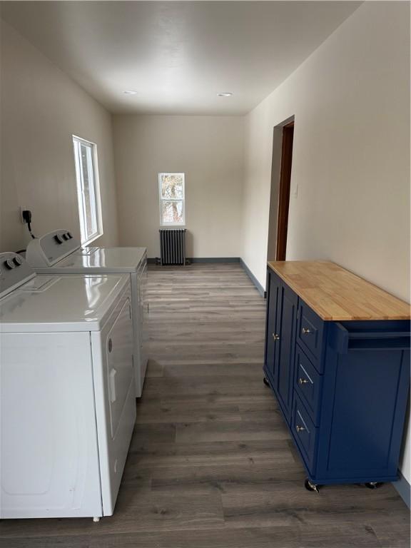 clothes washing area with radiator heating unit, dark hardwood / wood-style floors, and washing machine and dryer