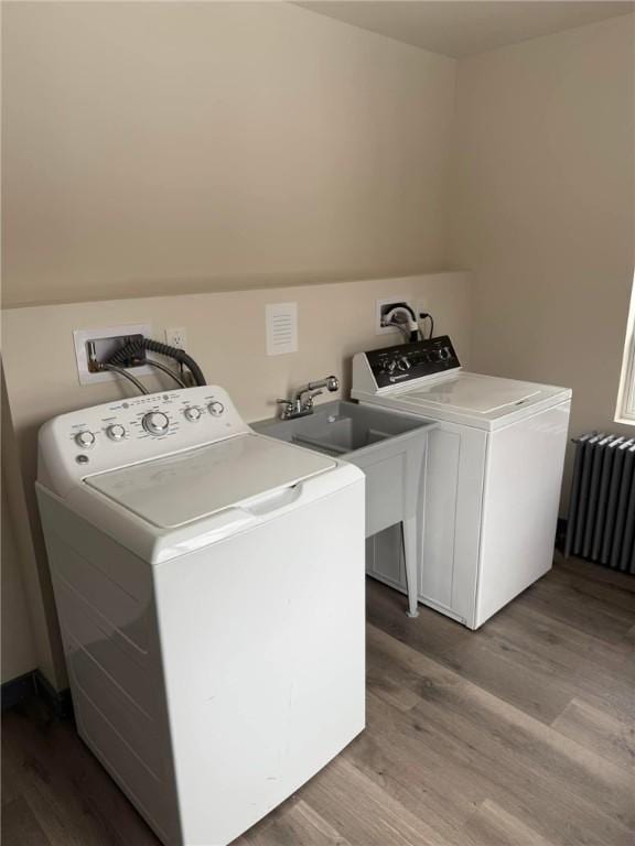 washroom with sink, radiator, hardwood / wood-style floors, and washer and dryer