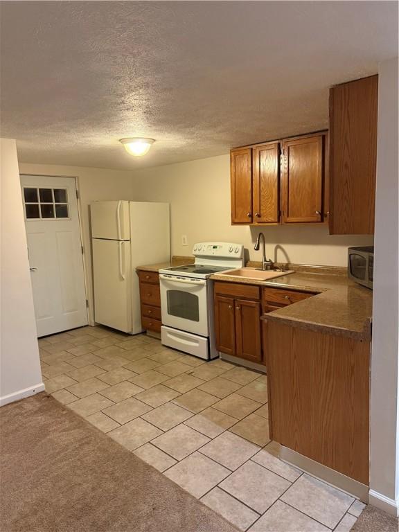 kitchen featuring sink, light carpet, a textured ceiling, and white appliances