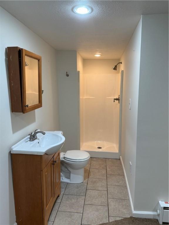 bathroom with tile patterned flooring, vanity, toilet, and a shower