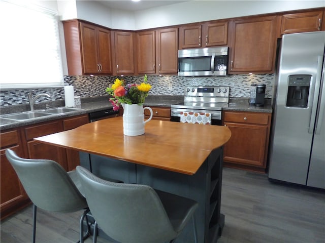 kitchen featuring appliances with stainless steel finishes, backsplash, dark wood-type flooring, sink, and a kitchen island