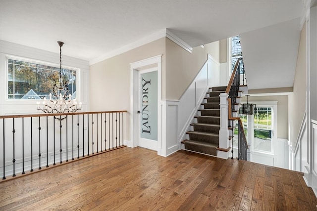 interior space with crown molding, wood-type flooring, and an inviting chandelier