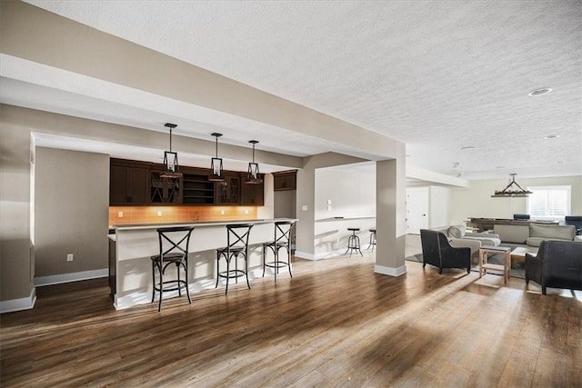 kitchen featuring a breakfast bar, a textured ceiling, dark brown cabinetry, and dark hardwood / wood-style flooring