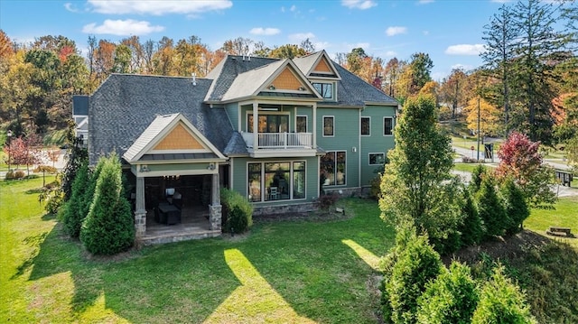 rear view of property featuring a garage, a lawn, and a balcony