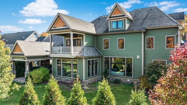 back of property with a balcony and a lawn