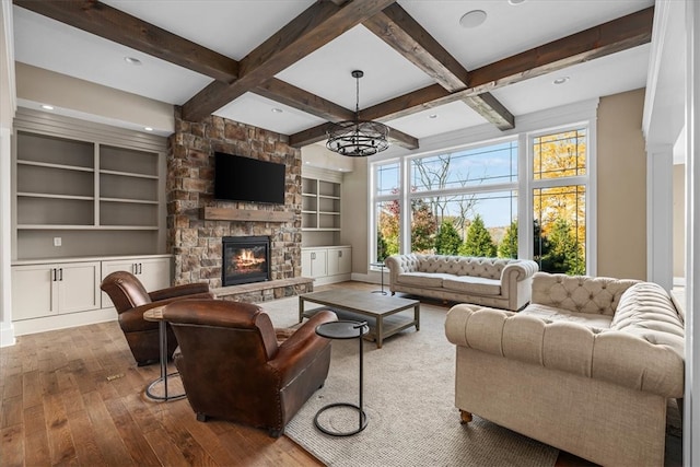 living room featuring a notable chandelier, hardwood / wood-style floors, beamed ceiling, and a fireplace