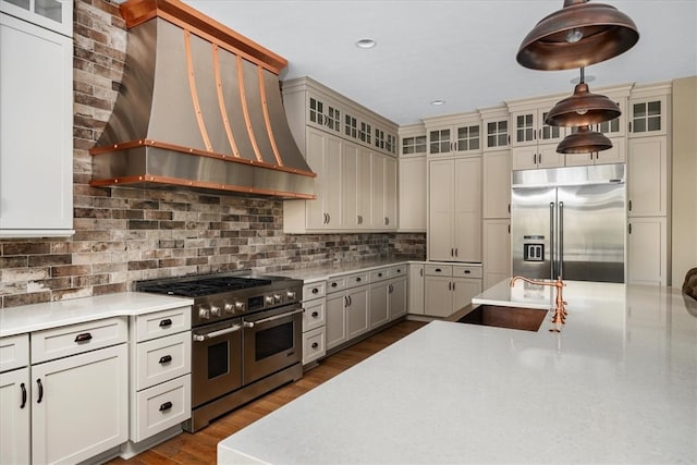 kitchen featuring custom exhaust hood, dark hardwood / wood-style floors, sink, high quality appliances, and decorative light fixtures