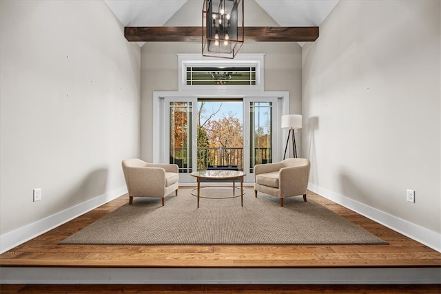 living area featuring a notable chandelier, wood-type flooring, and lofted ceiling with beams