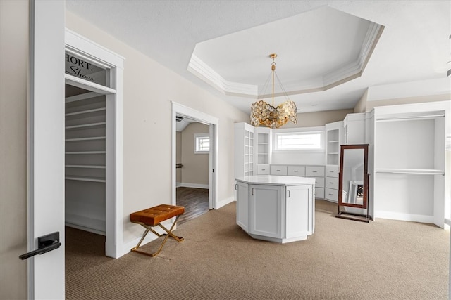 kitchen featuring a kitchen island, white cabinetry, hanging light fixtures, and a tray ceiling