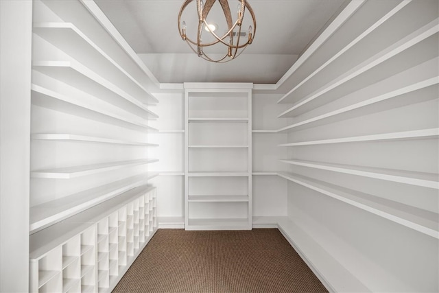 spacious closet with carpet flooring and an inviting chandelier