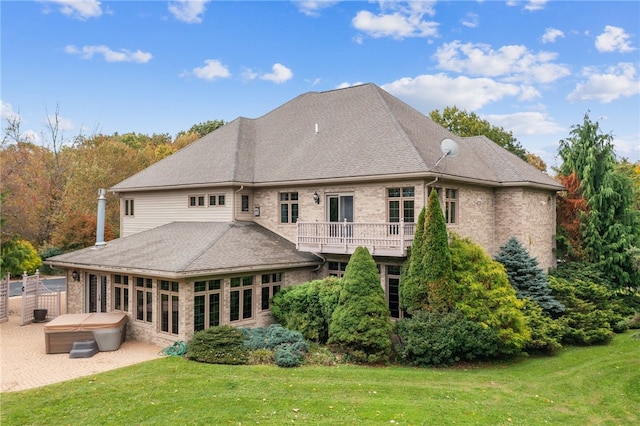 rear view of house with a hot tub, a patio area, and a lawn