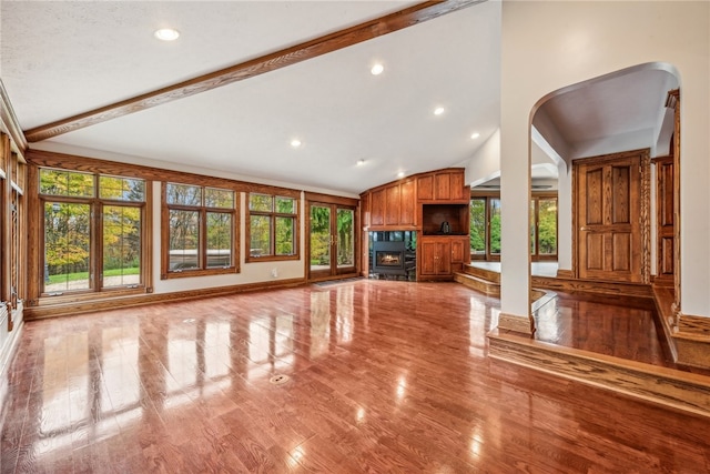 unfurnished living room with light hardwood / wood-style floors, lofted ceiling with beams, and plenty of natural light