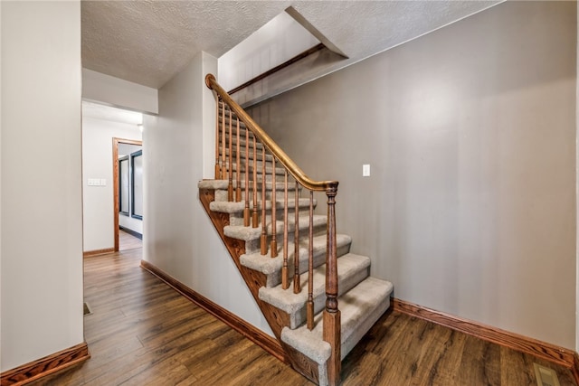 stairway with a textured ceiling and hardwood / wood-style flooring