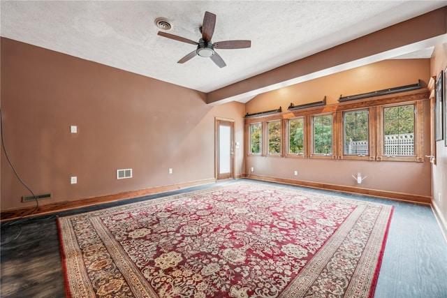 unfurnished room with a healthy amount of sunlight, a textured ceiling, and dark hardwood / wood-style floors