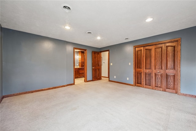 unfurnished bedroom with connected bathroom and light colored carpet