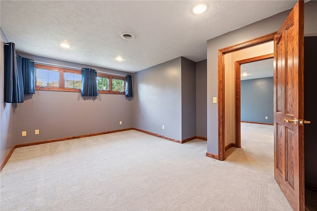 spare room with a textured ceiling and light colored carpet