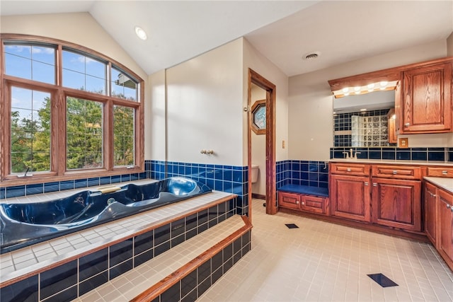 bathroom featuring a bathing tub, vanity, tile patterned floors, and vaulted ceiling