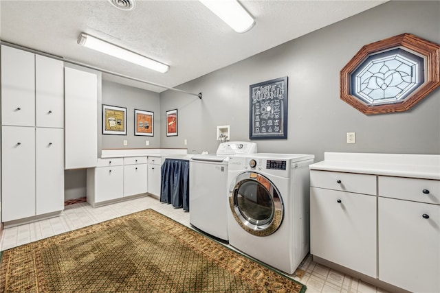 washroom featuring cabinets, washer and dryer, and a textured ceiling