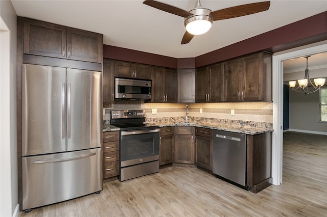 kitchen featuring light stone countertops, light hardwood / wood-style floors, tasteful backsplash, and appliances with stainless steel finishes