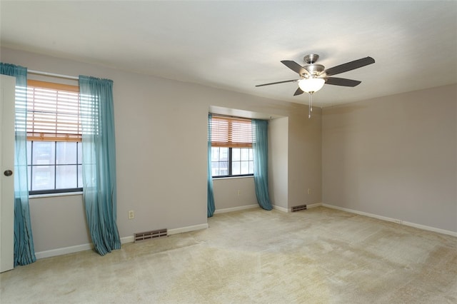 carpeted spare room featuring ceiling fan and plenty of natural light