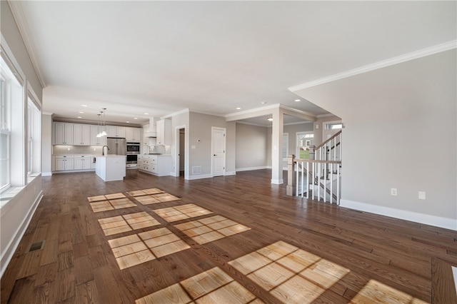 unfurnished living room with ornamental molding, sink, and dark hardwood / wood-style floors