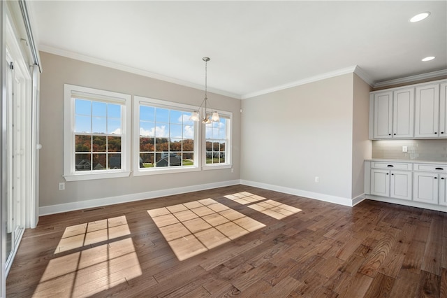 unfurnished dining area featuring ornamental molding, dark hardwood / wood-style floors, and an inviting chandelier