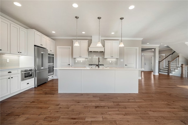 kitchen with appliances with stainless steel finishes, premium range hood, white cabinetry, dark hardwood / wood-style floors, and pendant lighting