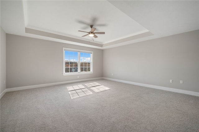 carpeted spare room with ceiling fan, crown molding, and a tray ceiling