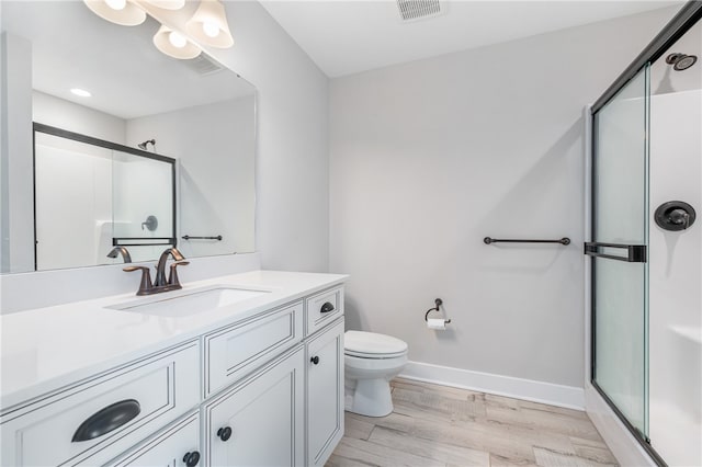 bathroom featuring vanity, toilet, walk in shower, and hardwood / wood-style floors