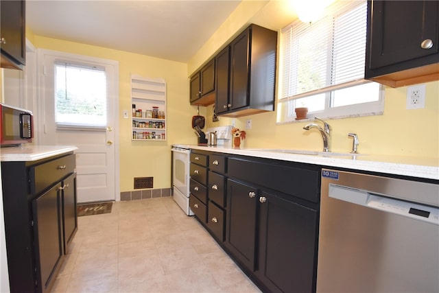 kitchen featuring sink, dishwasher, light tile patterned floors, and white range oven