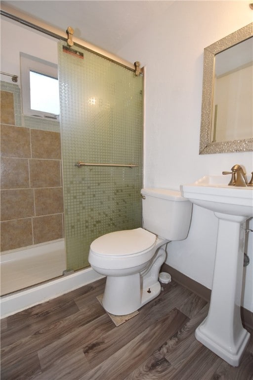 bathroom with a shower with shower door, hardwood / wood-style flooring, and toilet