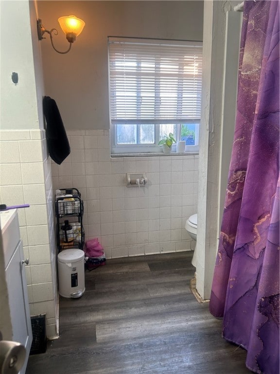 bathroom featuring wood-type flooring, tile walls, toilet, vanity, and a shower with shower curtain